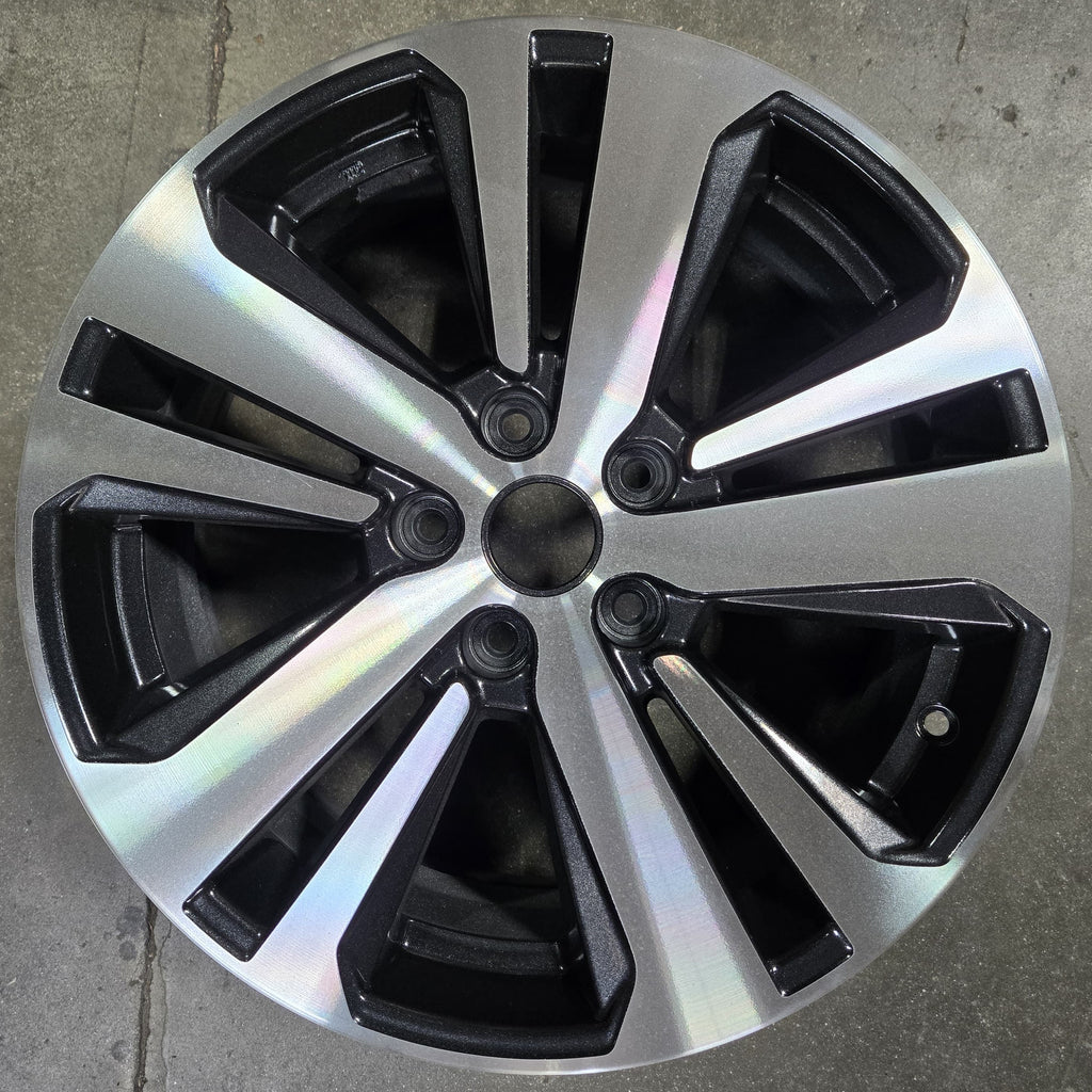 Car wheel rim with black and silver design on a concrete floor
