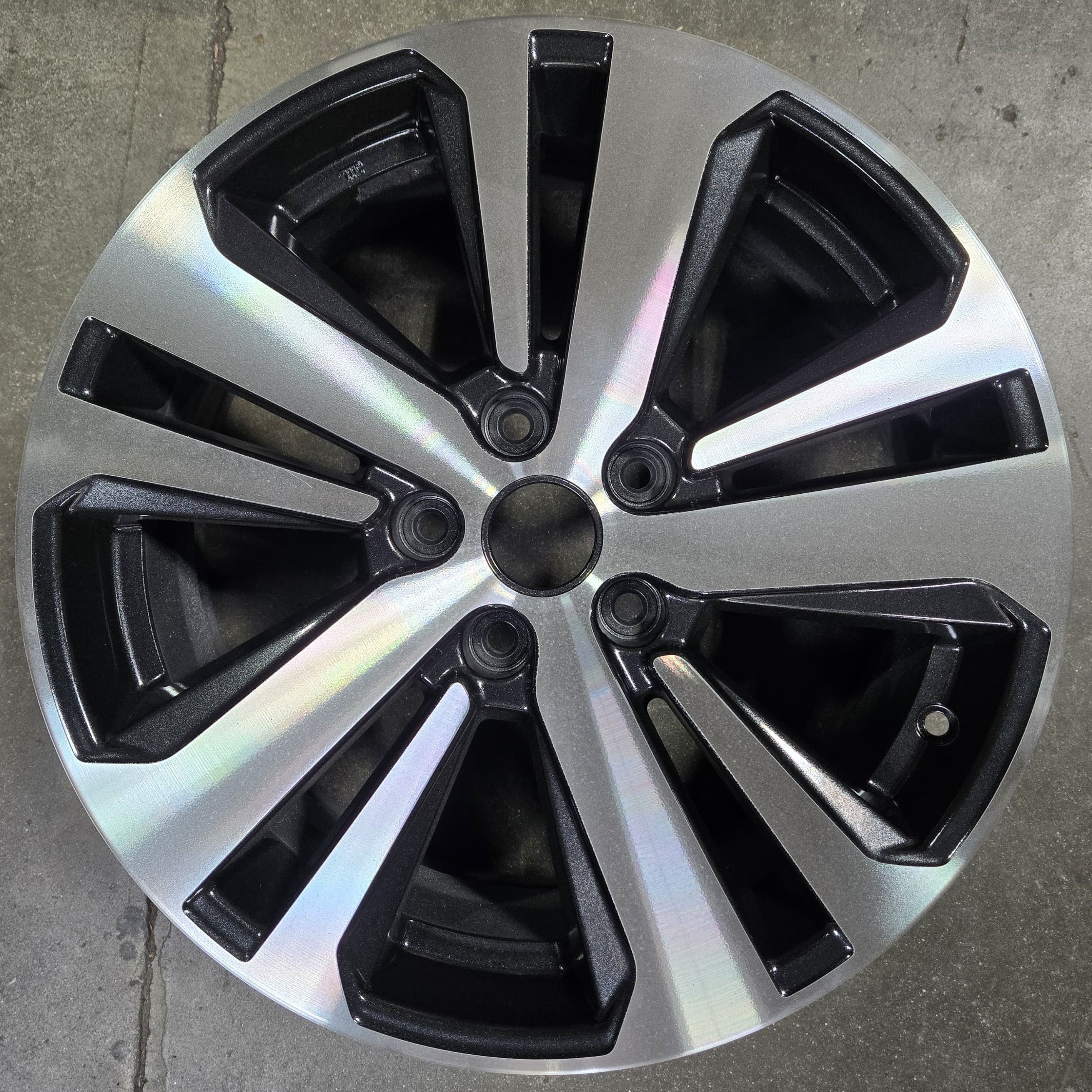 Car wheel rim with black and silver design on a concrete floor