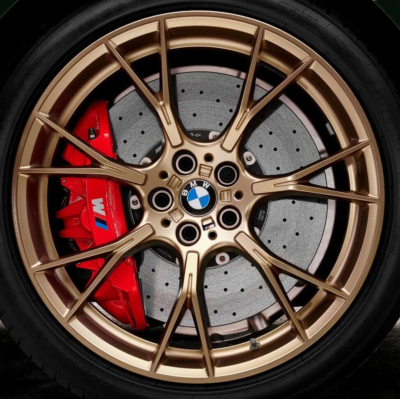 Close-up of a BMW wheel with gold finish and red brake caliper.