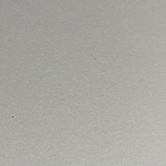 A close-up of a light gray textured surface, likely a fabric or paper swatch.