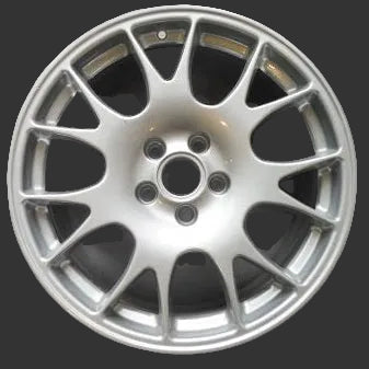 A silver multi-spoke alloy car wheel rim photographed from above on a plain gray surface.