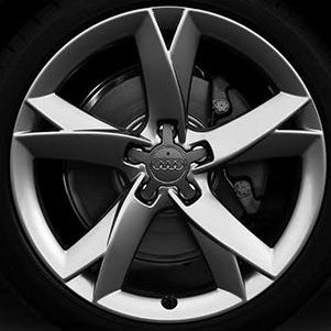 Close-up of a silver multi-spoke alloy wheel with a black tire and visible brake caliper, featuring the Audi logo in the center.