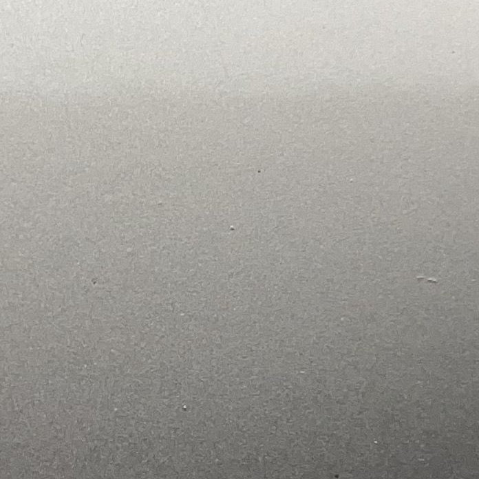 A close-up of a smooth, matte gray surface with a subtle gradient from lighter gray at the top to darker gray at the bottom.