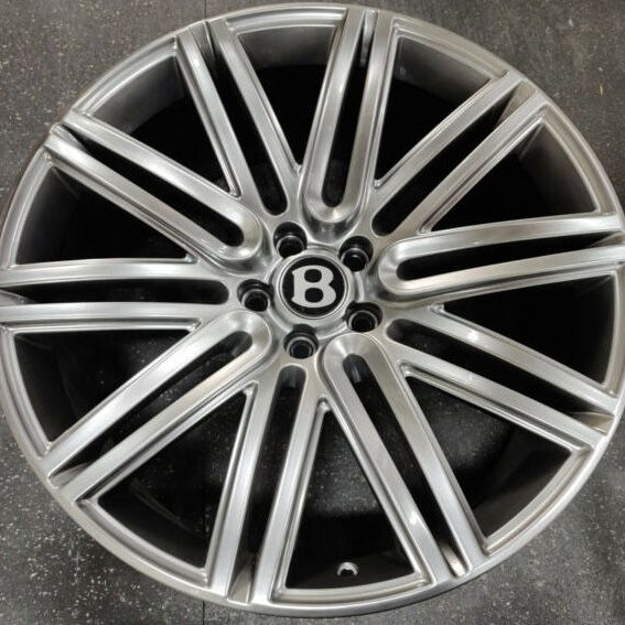 Silver car wheel rim with Bentley logo on a dark background