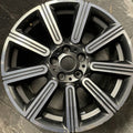 Close-up of a metallic car wheel rim on a stone surface