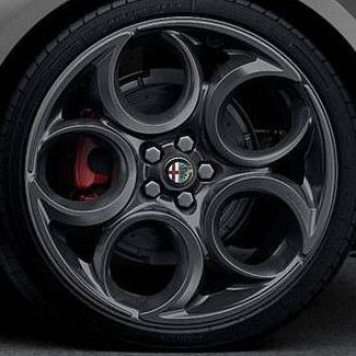 Close-up of a car wheel with a distinctive rim design featuring the Alfa Romeo logo.