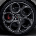 Close-up of a car wheel with a distinctive rim design featuring the Alfa Romeo logo.