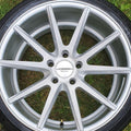 Close-up of a silver alloy wheel with 'Vossen' logo on grass