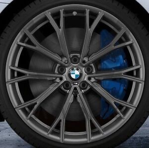 A close-up of a dark gray multi-spoke alloy wheel with a blue brake caliper visible behind it, featuring the BMW logo in the center.