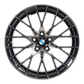 A multi-spoke alloy car wheel rim in a dark metallic gray finish, featuring the BMW logo in the center, set against a plain white background.